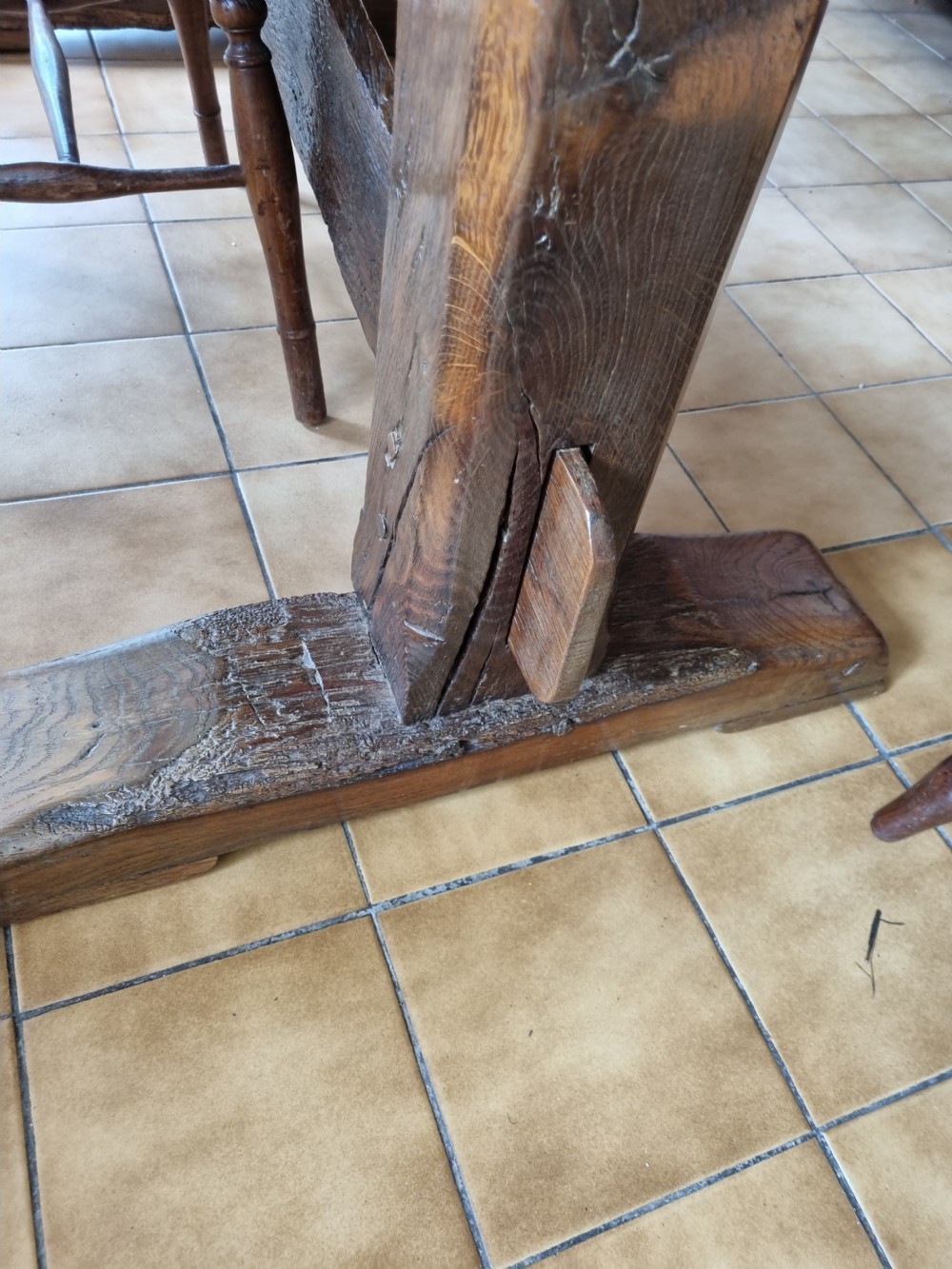 An antique dark oak refectory dining table featuring a plank top supported by a sturdy trestle base. View V
