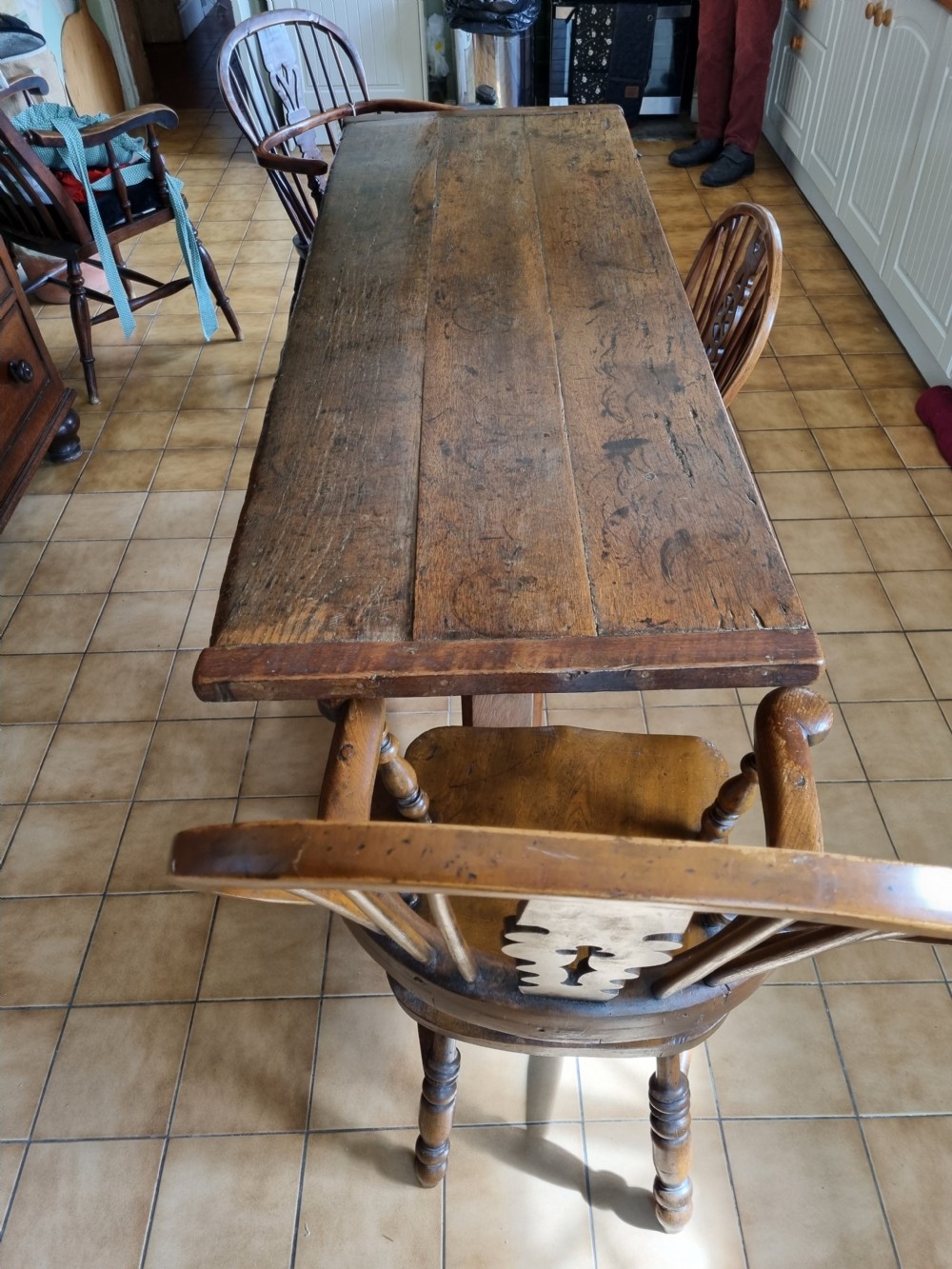An antique dark oak refectory dining table featuring a plank top supported by a sturdy trestle base. View VI