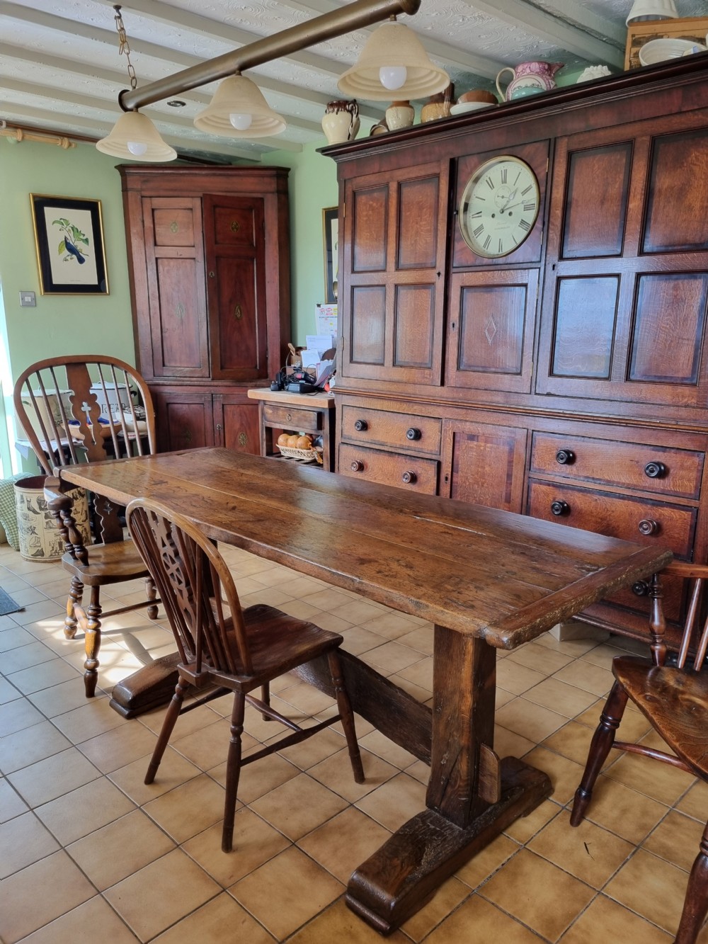 An antique dark oak refectory dining table featuring a plank top supported by a sturdy trestle base. View VII