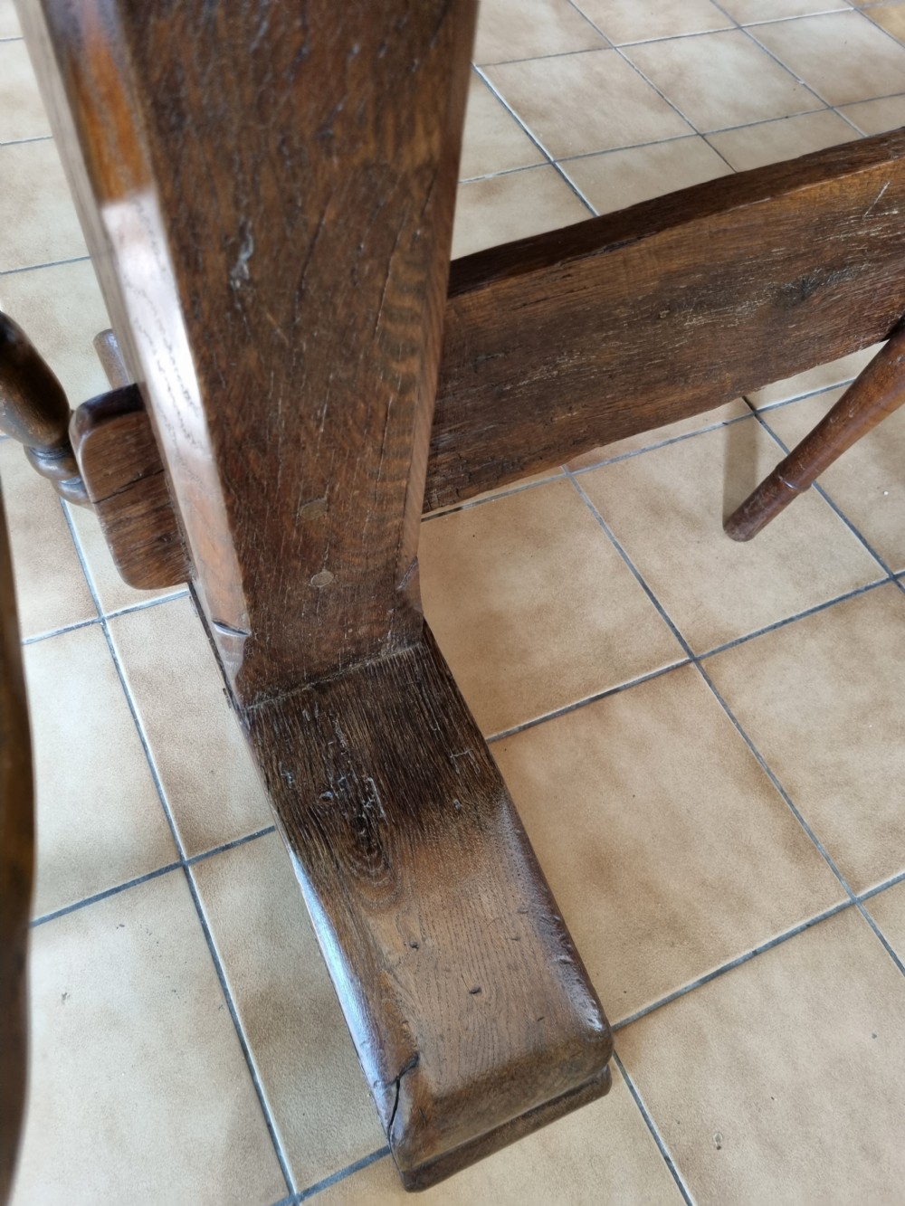 An antique dark oak refectory dining table featuring a plank top supported by a sturdy trestle base. View VIII