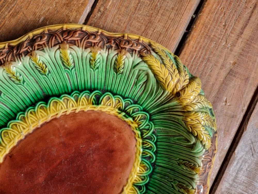 An oval Victorian majolica earthenware bread plate featuring a brown central field surrounded by moulded green and yellow wheat motifs. View II