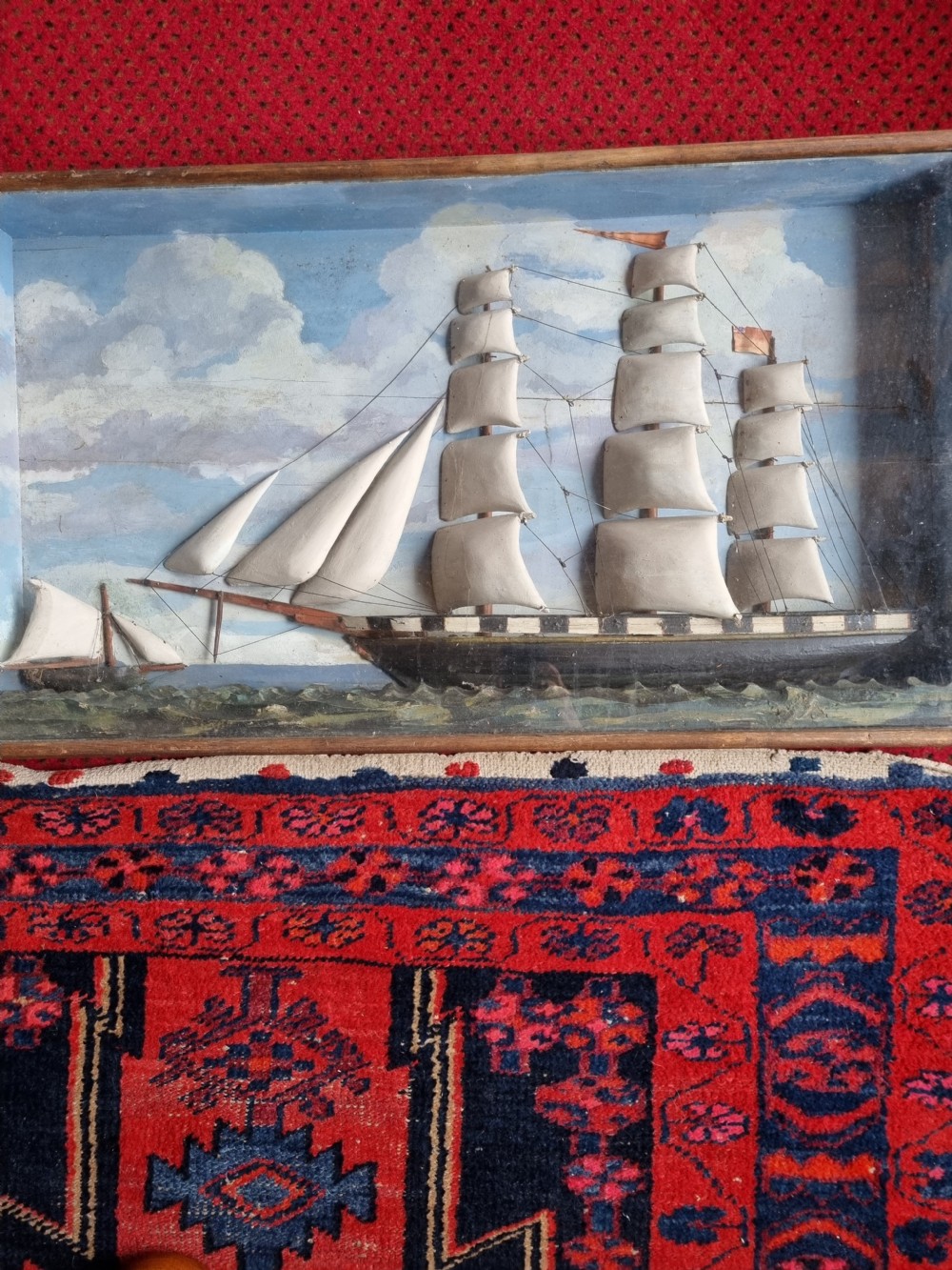 A framed three-dimensional naive wooden diorama depicting a multi-masted sailing ship on a painted sea against a cloudy sky background. View VI