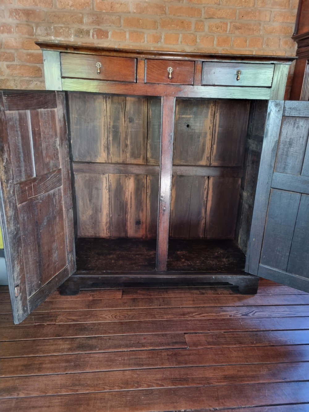 An 18th-century dark oak Welsh hanging cupboard featuring three upper drawers above double raised-panel doors. View III