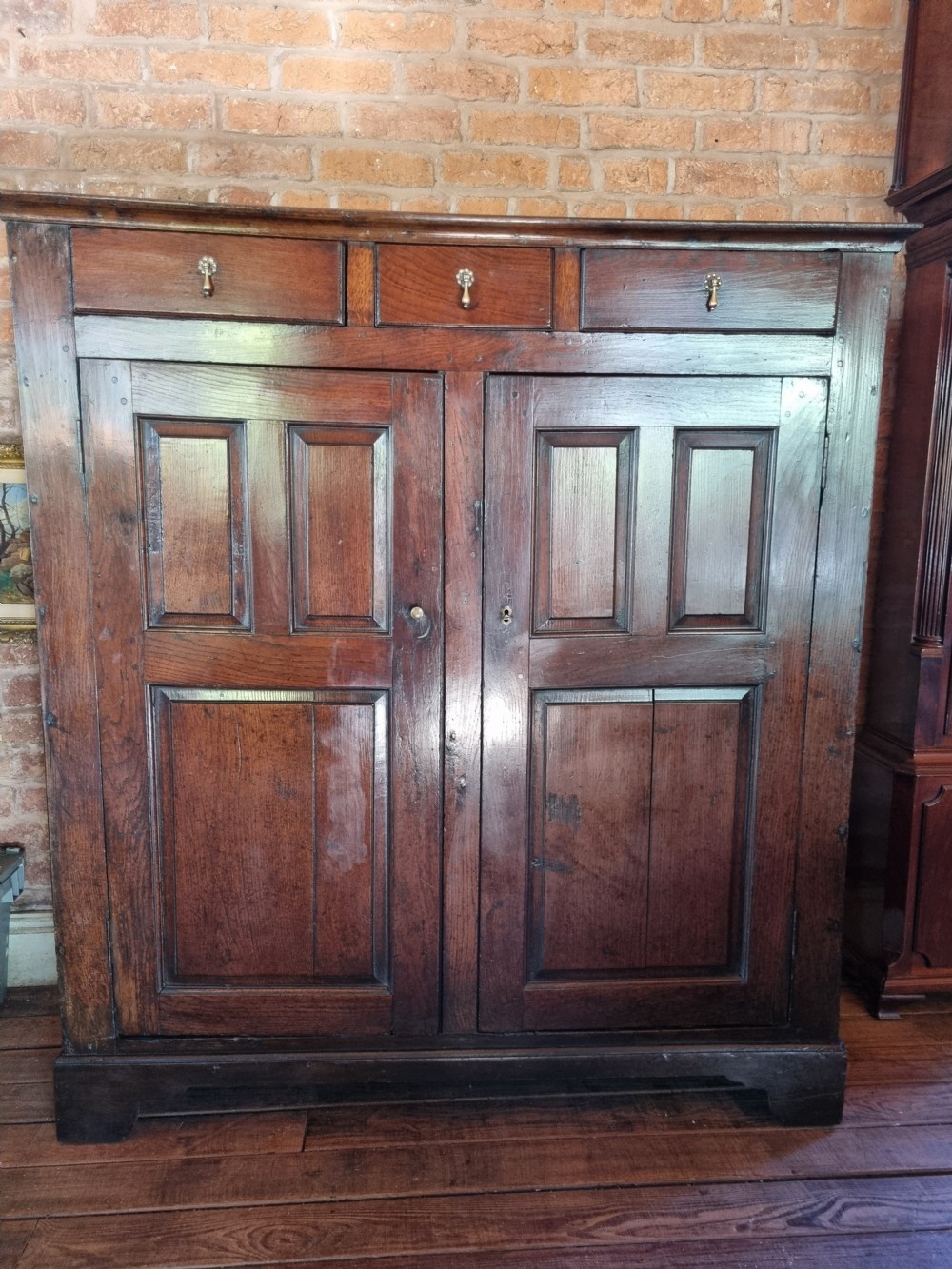 An 18th-century dark oak Welsh hanging cupboard featuring three upper drawers above double raised-panel doors. View VIII
