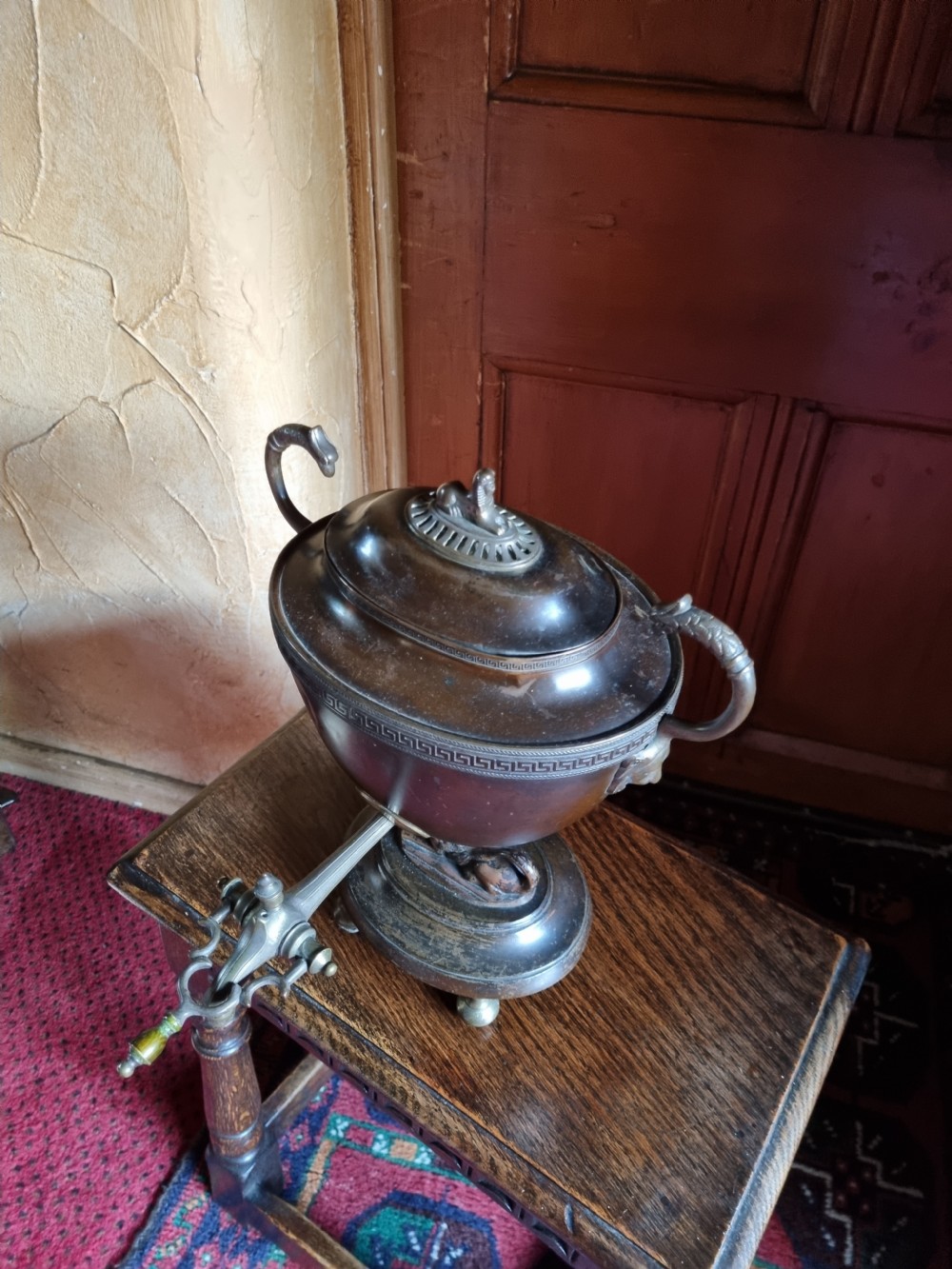 A dark patinated bronze and copper Regency tea samovar featuring a Greek key engraved border, side handles, spigoted tap, and pedestal base. View V