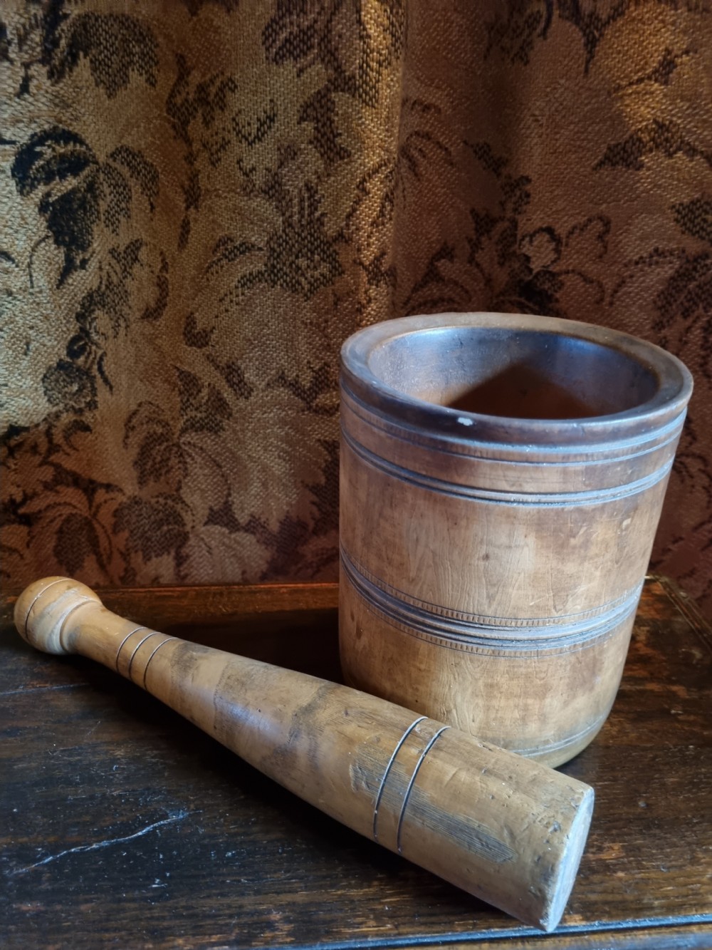 An 18th-century turned wooden mortar with a matching pestle showing hand-carved decorative outer rings. View V