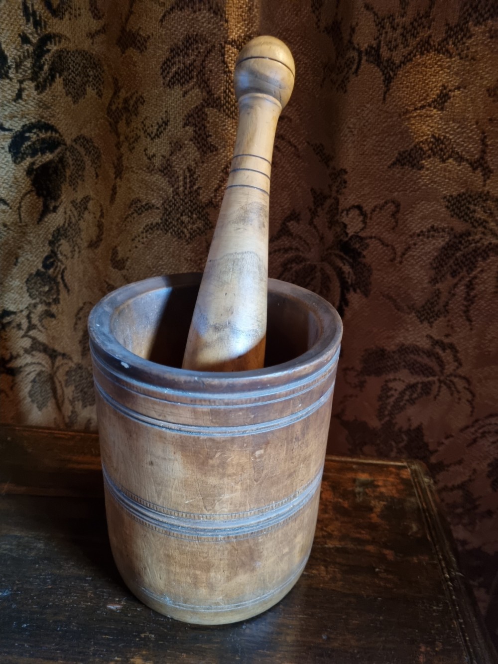 An 18th-century turned wooden mortar with a matching pestle showing hand-carved decorative outer rings. View VI