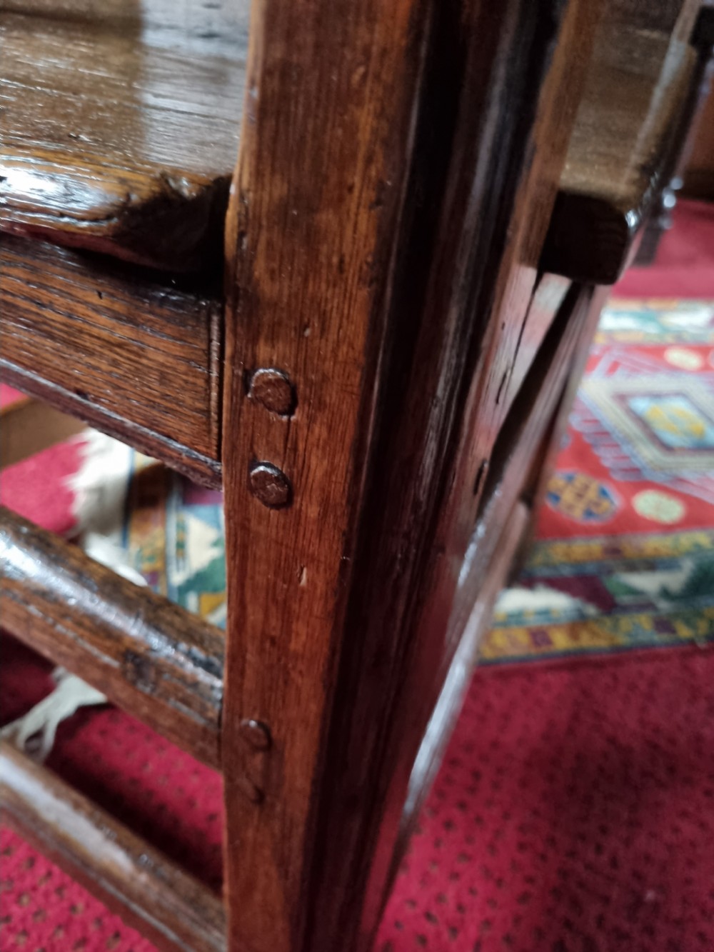 A late 17th-century solid dark oak masters armchair with a panelled backrest, flat armrests, and a wooden plank seat. View III