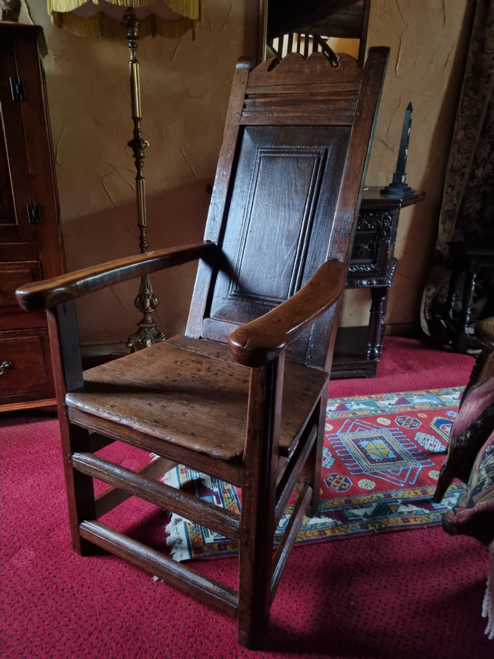 A late 17th-century solid dark oak masters armchair with a panelled backrest, flat armrests, and a wooden plank seat. View VI