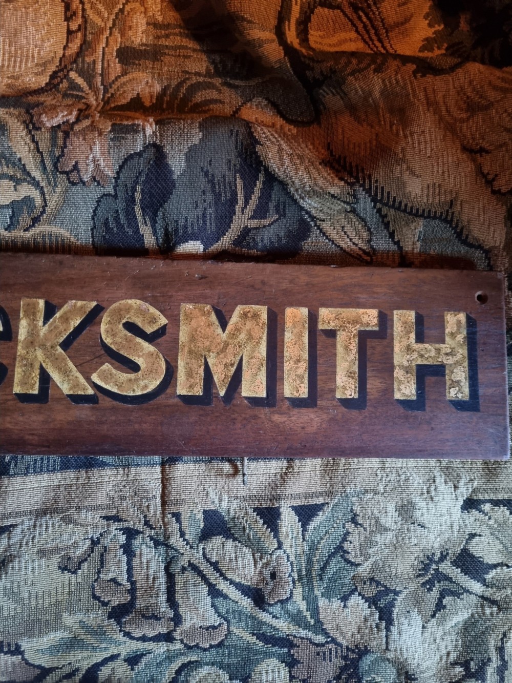 A rectangular dark oak board featuring raised gold lettering spelling the word LOCKSMITH. View III