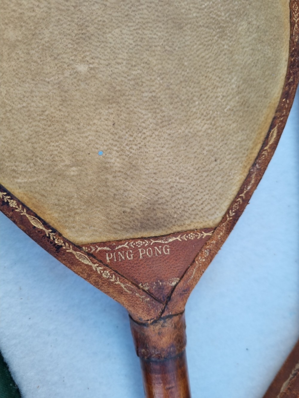 Pair of antique vellum ping pong bats with turned wooden handles displayed inside an open dark green box. View II