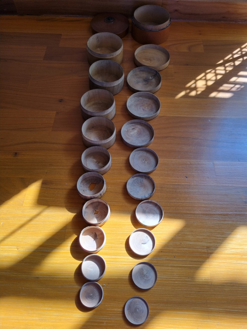 A set of 19th-century turned boxwood nesting containers with fitted lids displayed open on a wooden surface. View III