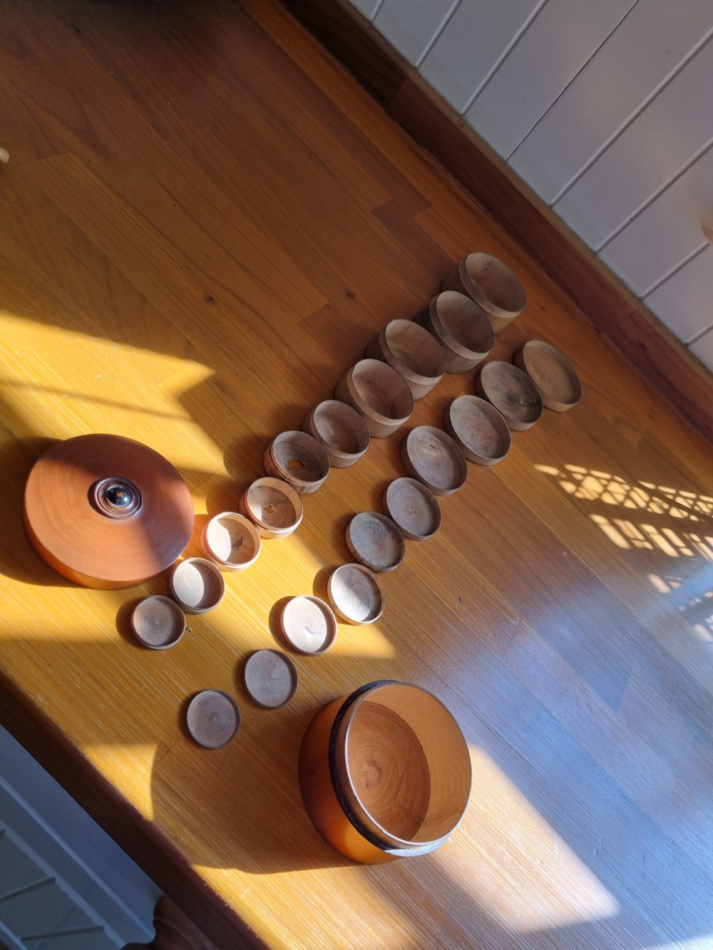 A set of 19th-century turned boxwood nesting containers with fitted lids displayed open on a wooden surface. View V