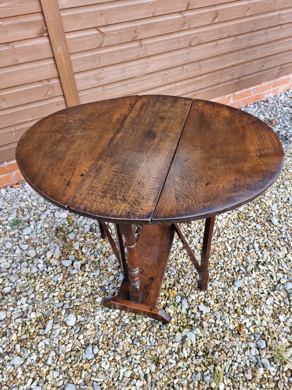 An eighteenth-century dark oak gateleg table featuring drop-down oval leaves, turned column supports, and a flat sleigh base. View V