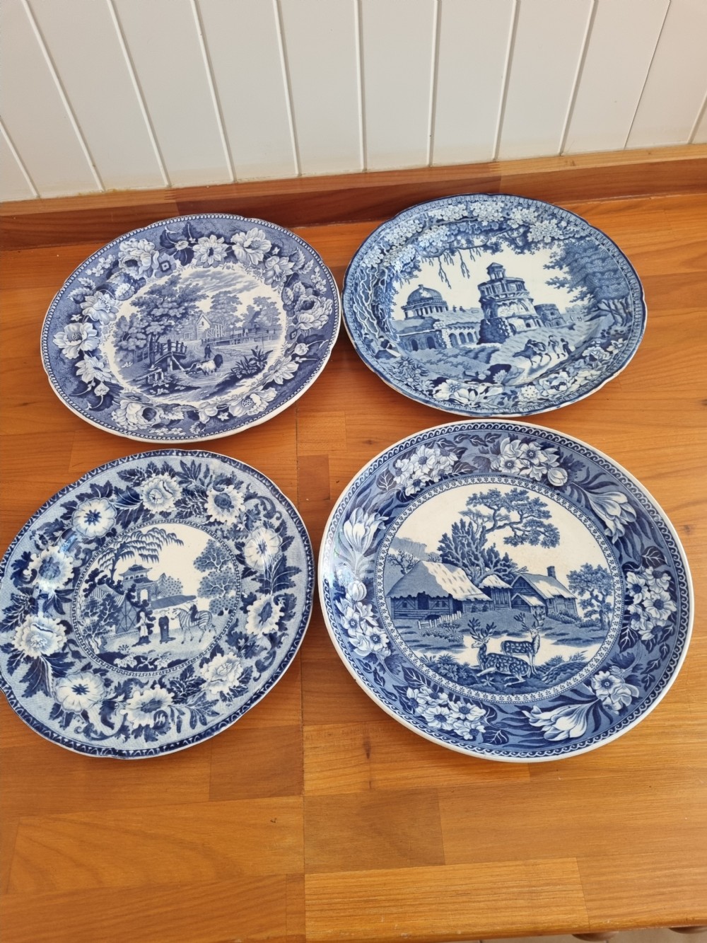 A set of four 19th-century blue and white transferware ceramic plates featuring detailed pictorial landscape scenes and floral borders. View XI