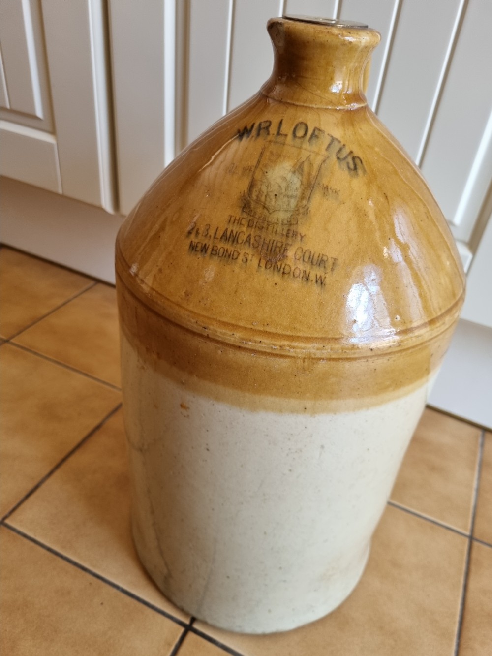 A nineteenth-century two-tone stoneware spirit jug featuring a brown glazed upper section with stamped text reading W.R. Loftus London above an off-white lower section. View II