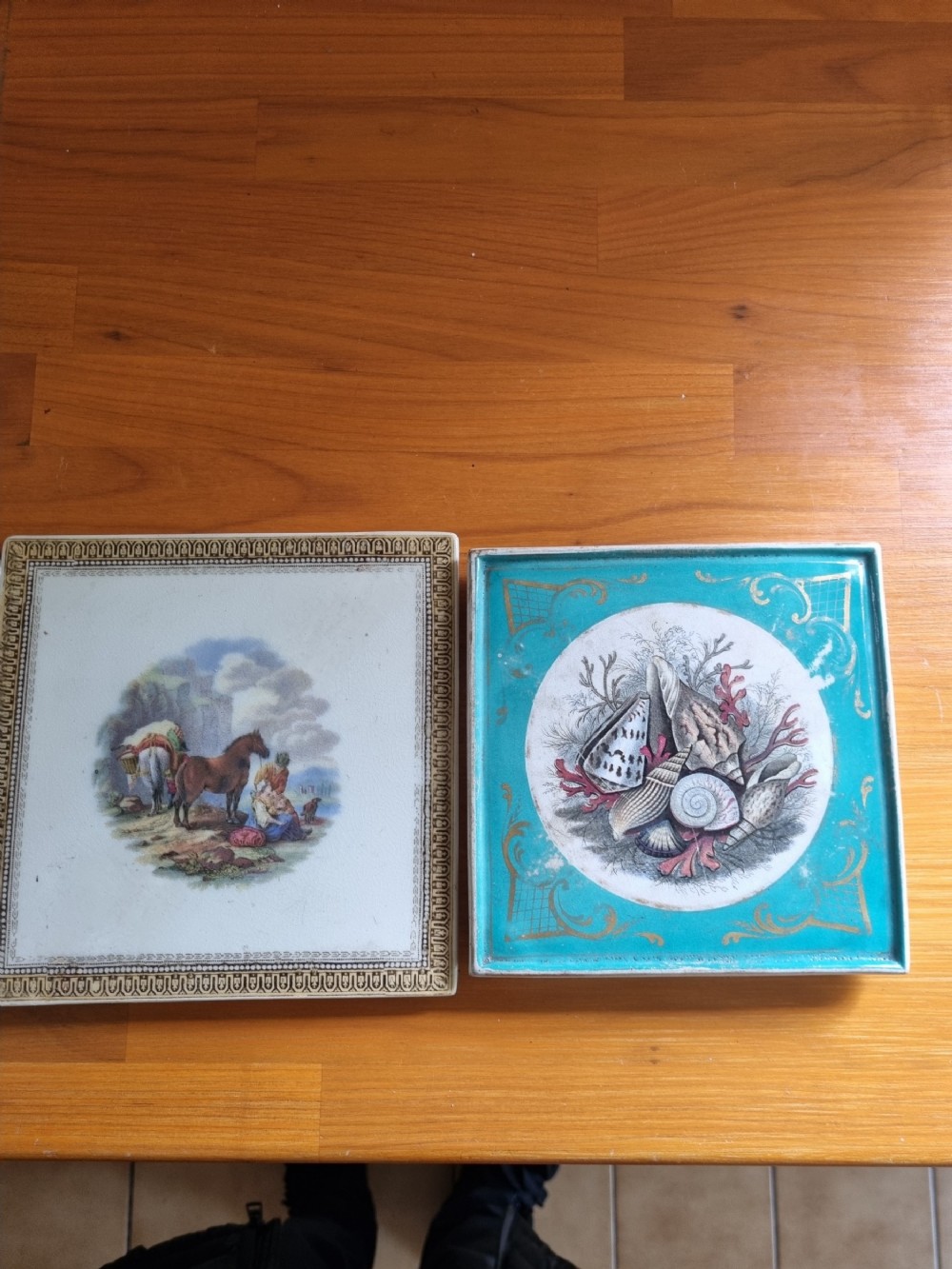 A pair of square Victorian Prattware ceramic teapot stands, one featuring a turquoise border with a marine shell medallion and the other featuring an ornate border with an equestrian scene.