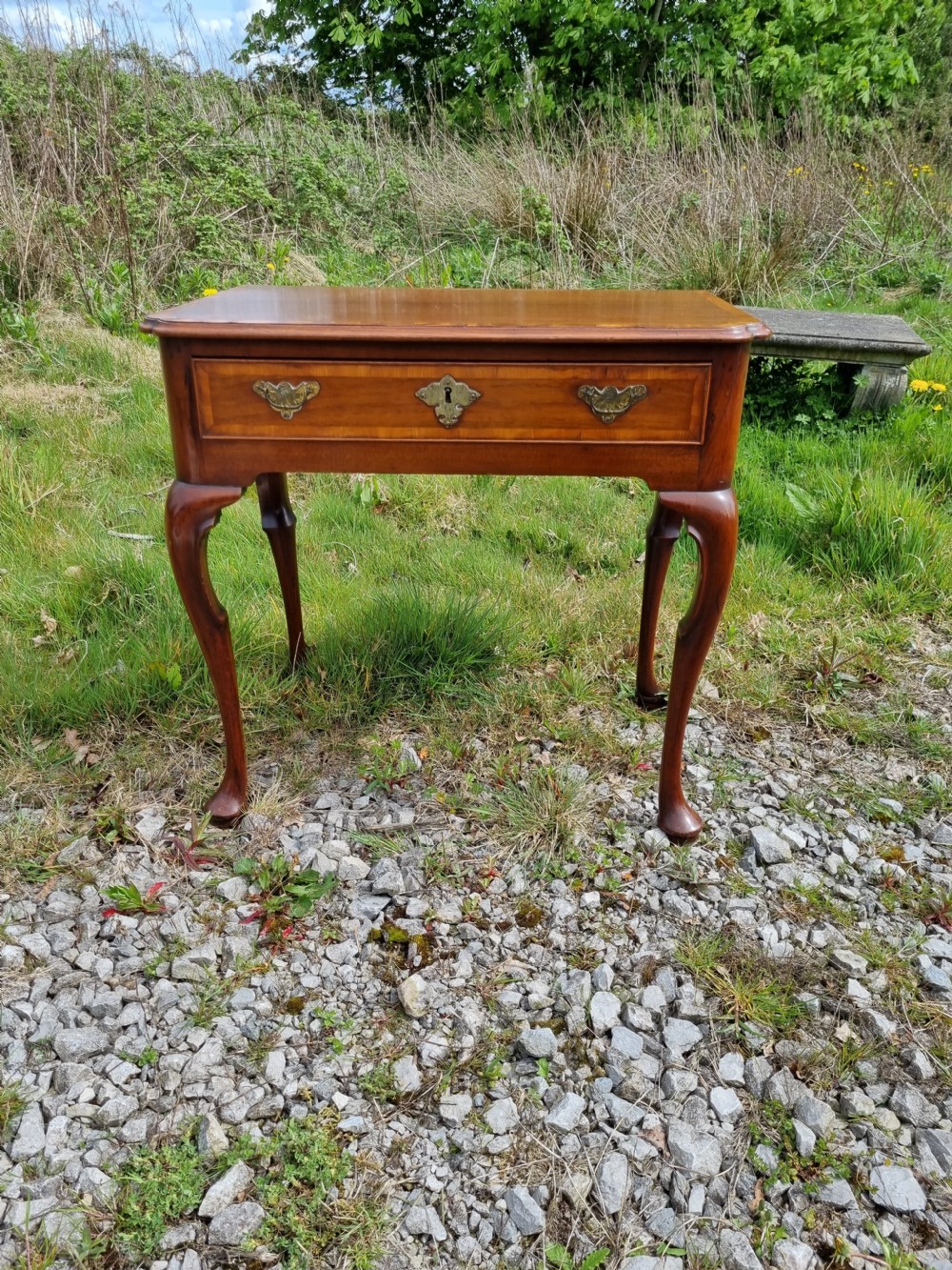 An Early Georgian walnut lowboy table featuring a single drawer with brass handles, crossbanded top border, and cabriole legs with pad feet. View III