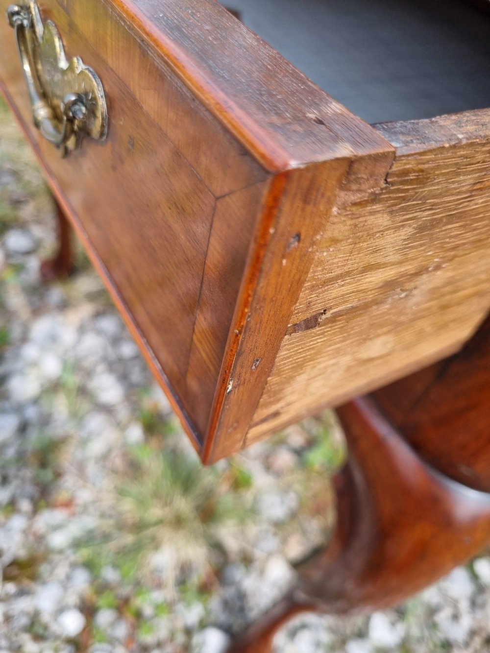 An Early Georgian walnut lowboy table featuring a single drawer with brass handles, crossbanded top border, and cabriole legs with pad feet. View V