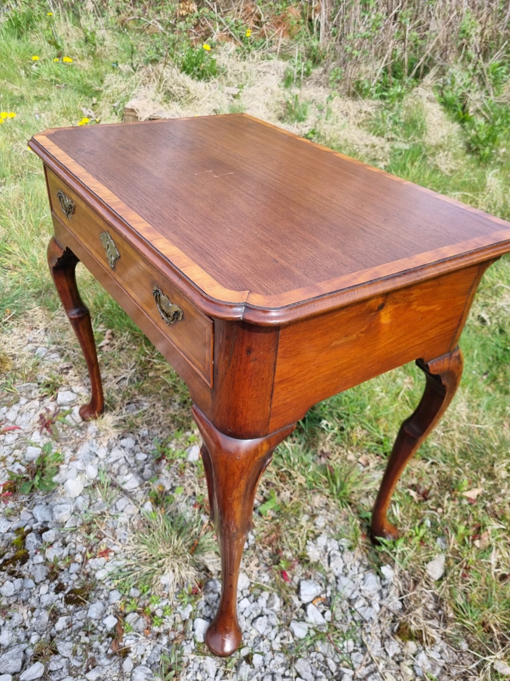 An Early Georgian walnut lowboy table featuring a single drawer with brass handles, crossbanded top border, and cabriole legs with pad feet. View IX