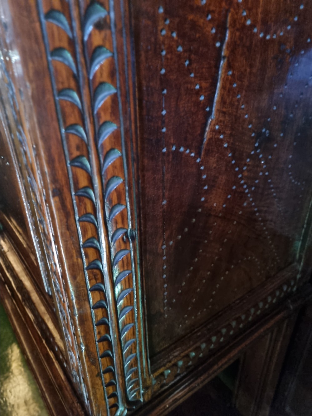 A 17th-century dark oak Lancashire buffet cupboard featuring three carved star-motif panel doors above turned support columns and a lower pot board shelf. View X