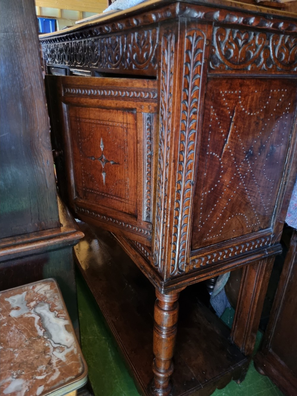 A 17th-century dark oak Lancashire buffet cupboard featuring three carved star-motif panel doors above turned support columns and a lower pot board shelf. View VIII