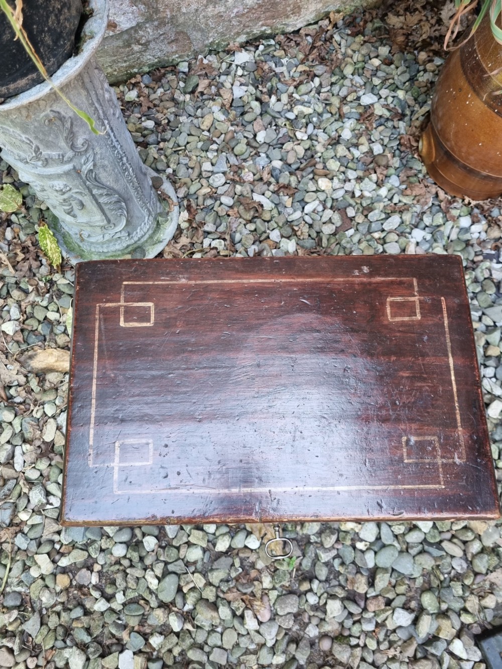 A 19th-century small dark painted Welsh coffer featuring geometric line-painted panel details, a hinged lid, and a key inserted into the front keyhole. View VI