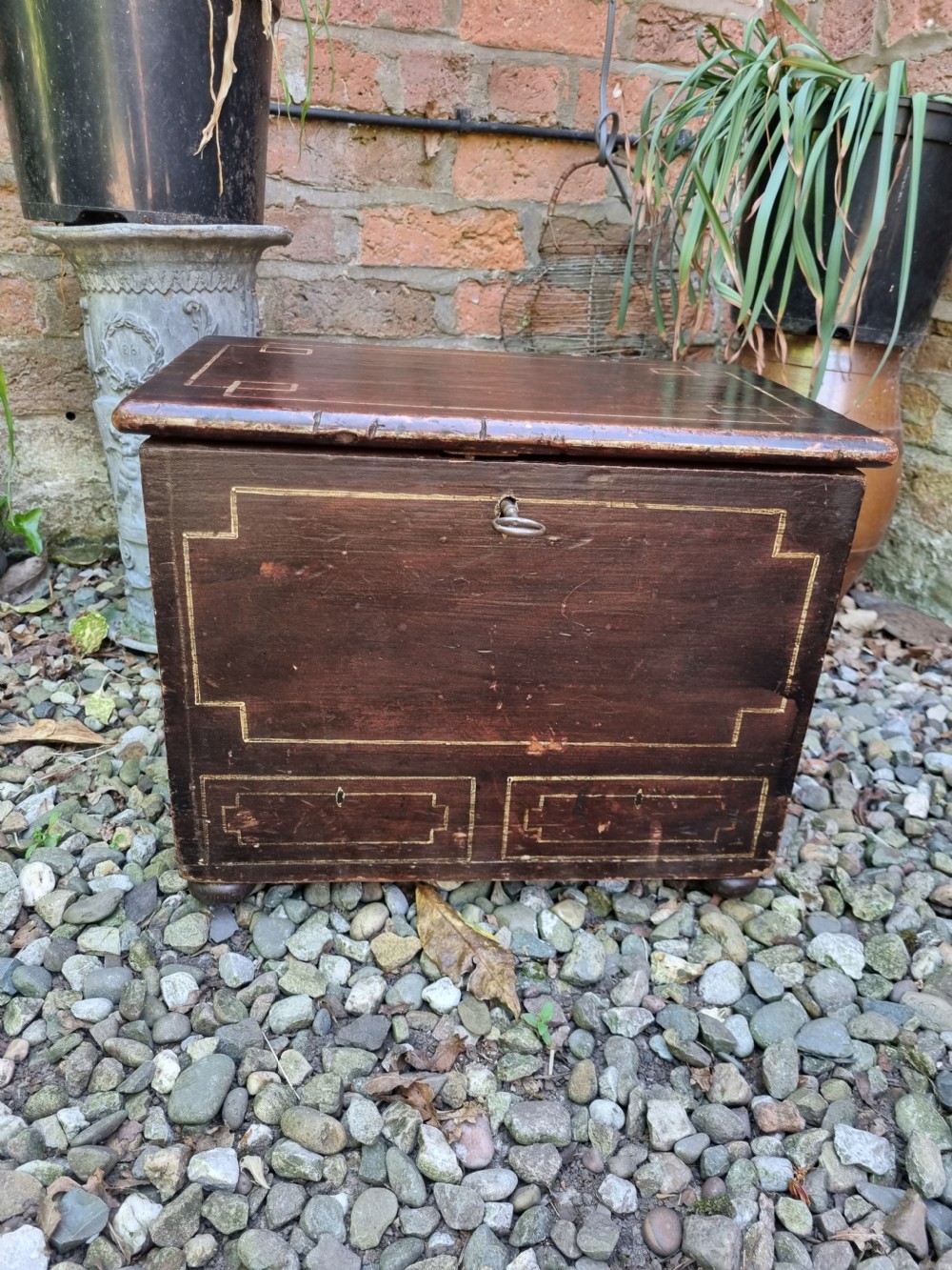 A 19th-century small dark painted Welsh coffer featuring geometric line-painted panel details, a hinged lid, and a key inserted into the front keyhole. View VIII