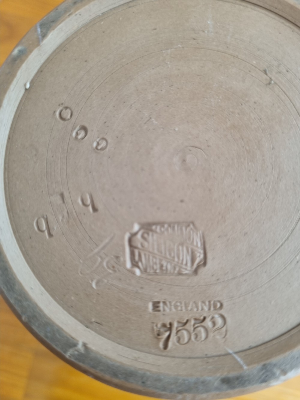 A cylindrical brown stoneware biscuit jar with a finial lid, featuring white sprigged relief lettering reading Anticipation above a figural scene. View V