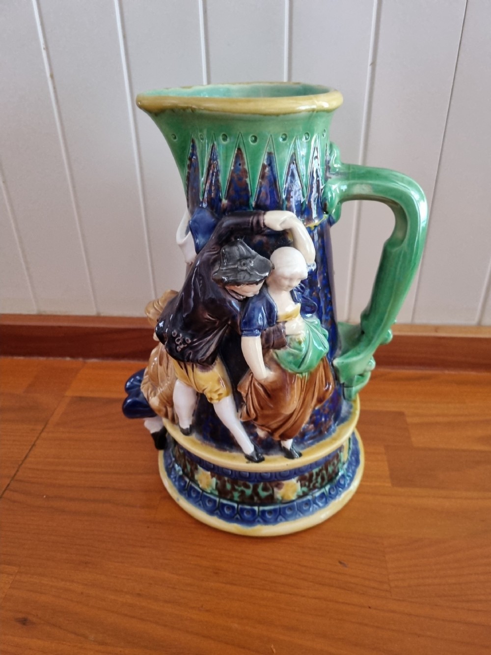 A Victorian Minton majolica ceramic jug decorated with high-relief figures of dancing couples in polychrome glazes against a dark blue background.