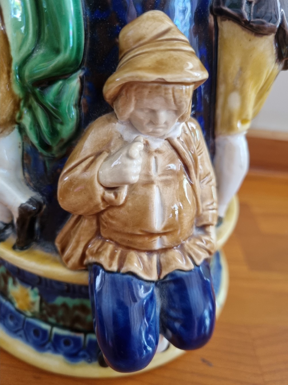 A Victorian Minton majolica ceramic jug decorated with high-relief figures of dancing couples in polychrome glazes against a dark blue background. View V