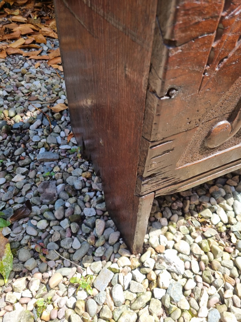 A late 17th-century dark oak coffer featuring a hinged lid, iron lockplate, and relief-carved front panel with foliate scroll motifs. View VI