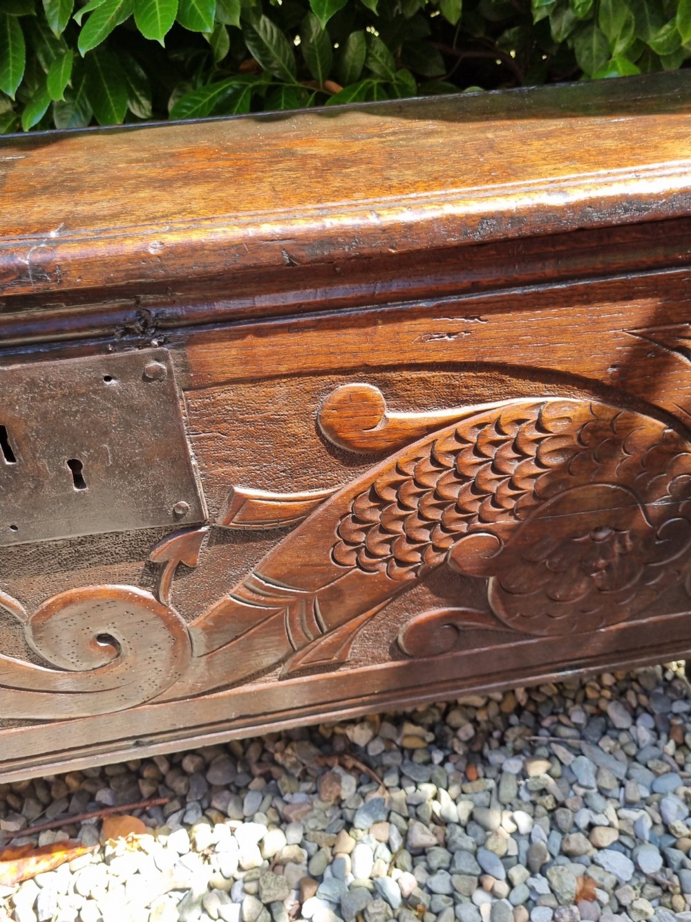 A late 17th-century dark oak coffer featuring a hinged lid, iron lockplate, and relief-carved front panel with foliate scroll motifs. View VII