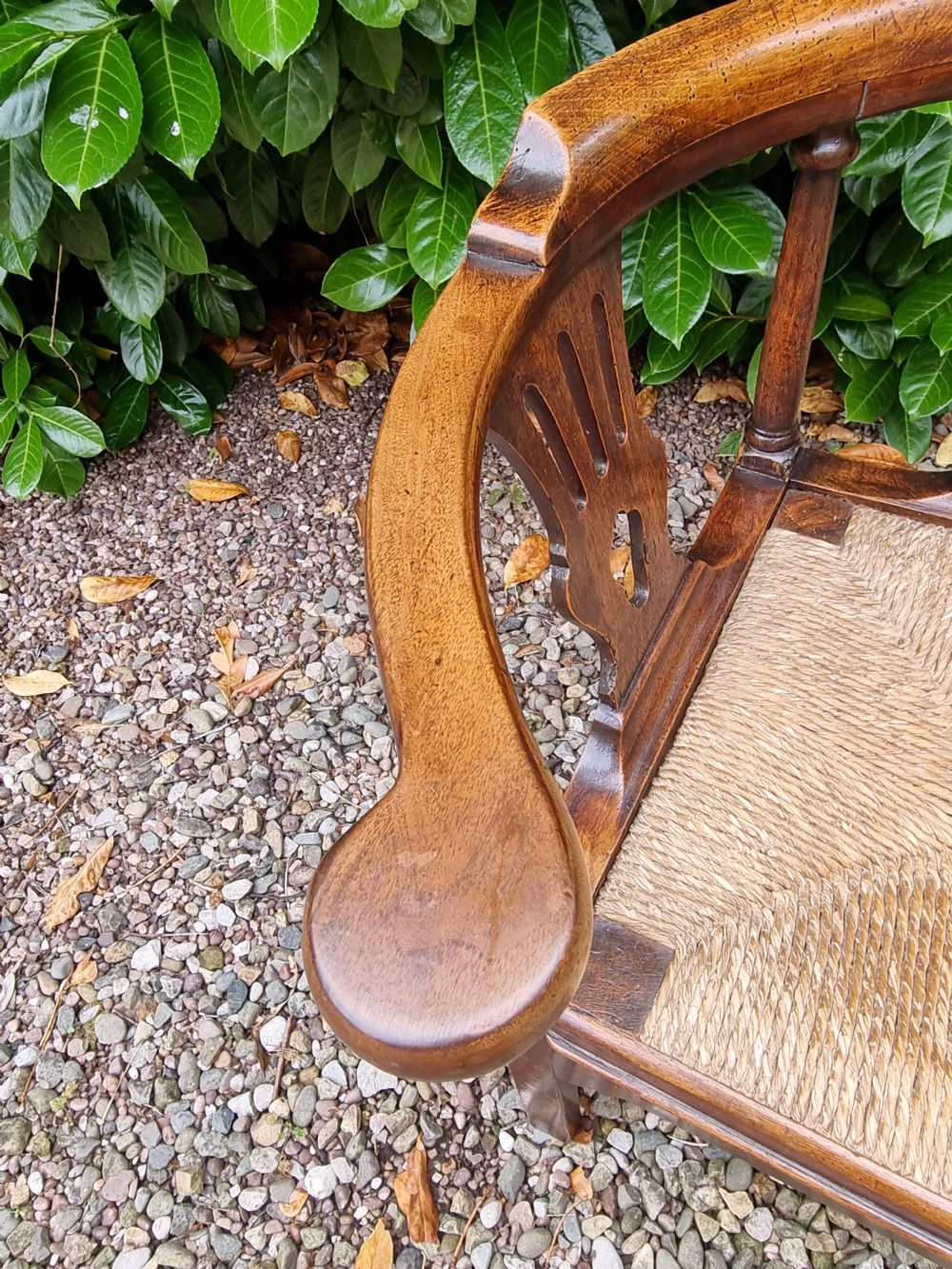 A Georgian oak corner chair featuring a curved top rail, two pierced back splats, a woven rush seat, and square legs. View III