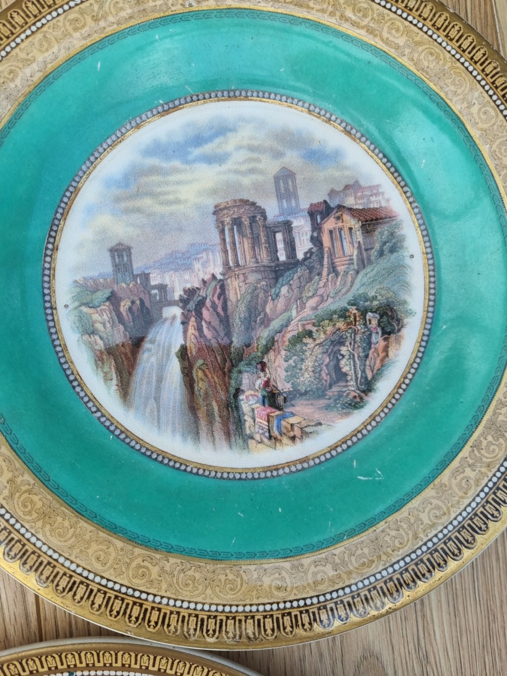 A collection of five 19th-century Prattware earthenware plates featuring central pictorial transfer prints enclosed by maroon and teal borders with gilded detailing. View V