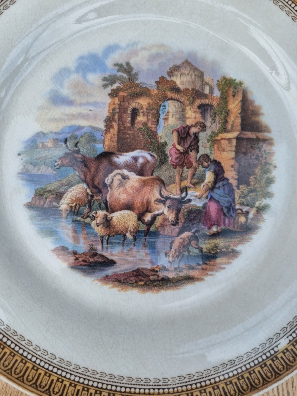 A set of five circular Victorian Prattware ceramic plates featuring polychrome transfer-printed pastoral landscape scenes with decorative gold geometric borders. View VII