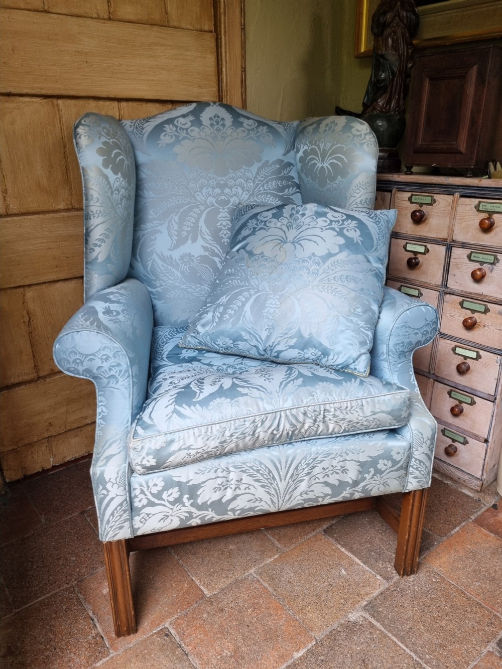 An antique high-backed wing armchair upholstered in ice blue patterned damask fabric with tapered square mahogany legs. View IV