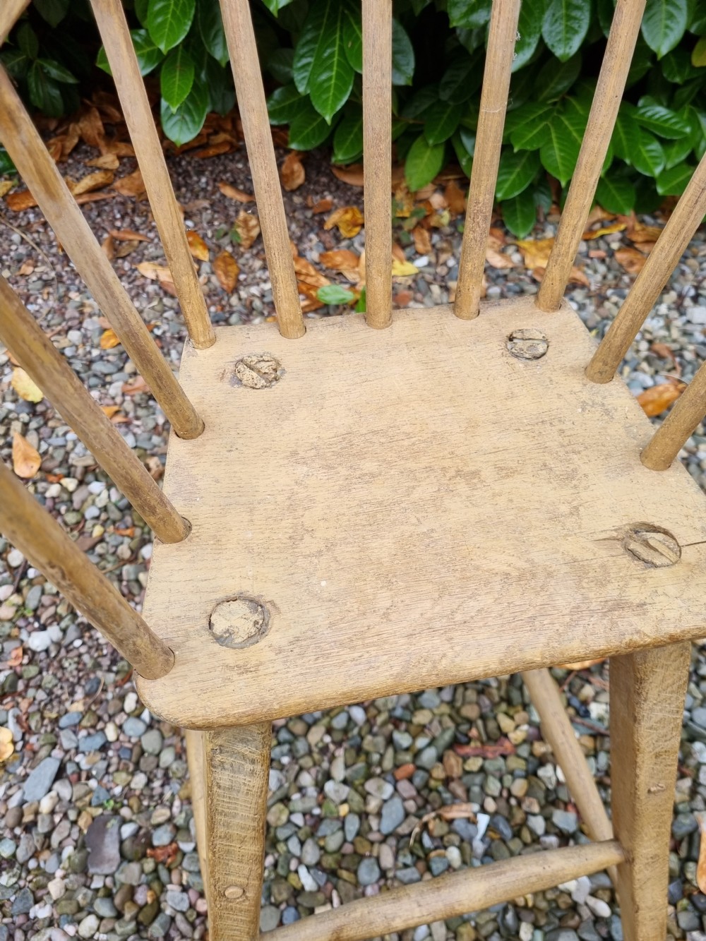 A 19th-century naive childs high chair made from natural ash and elm wood, featuring a spindle back, armrests, and splayed legs with stretchers. View II