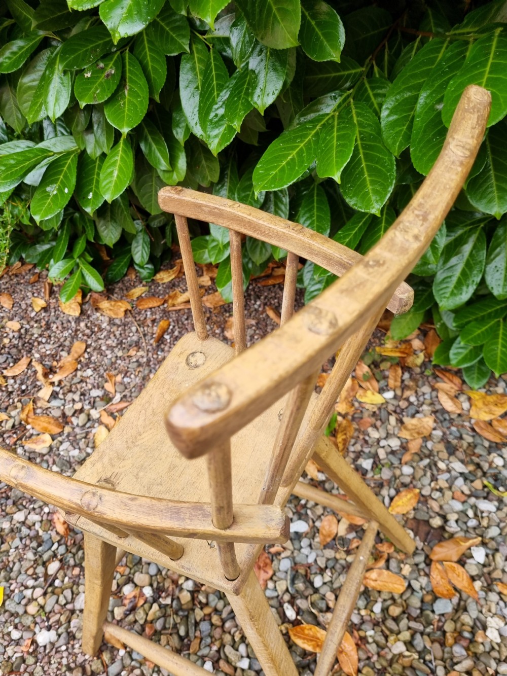A 19th-century naive childs high chair made from natural ash and elm wood, featuring a spindle back, armrests, and splayed legs with stretchers. View IV
