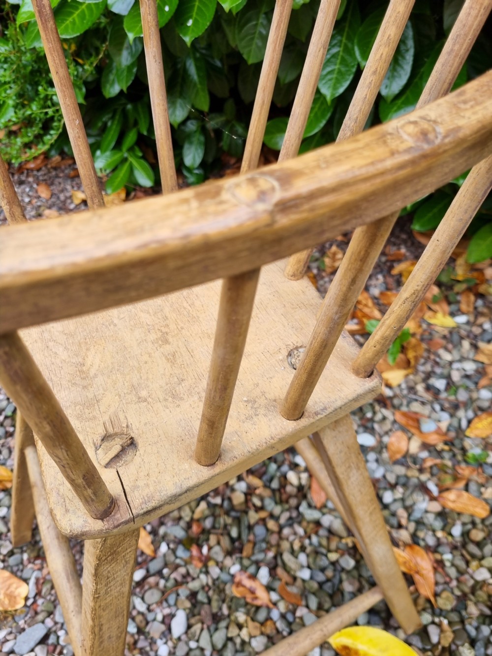 A 19th-century naive childs high chair made from natural ash and elm wood, featuring a spindle back, armrests, and splayed legs with stretchers. View VII