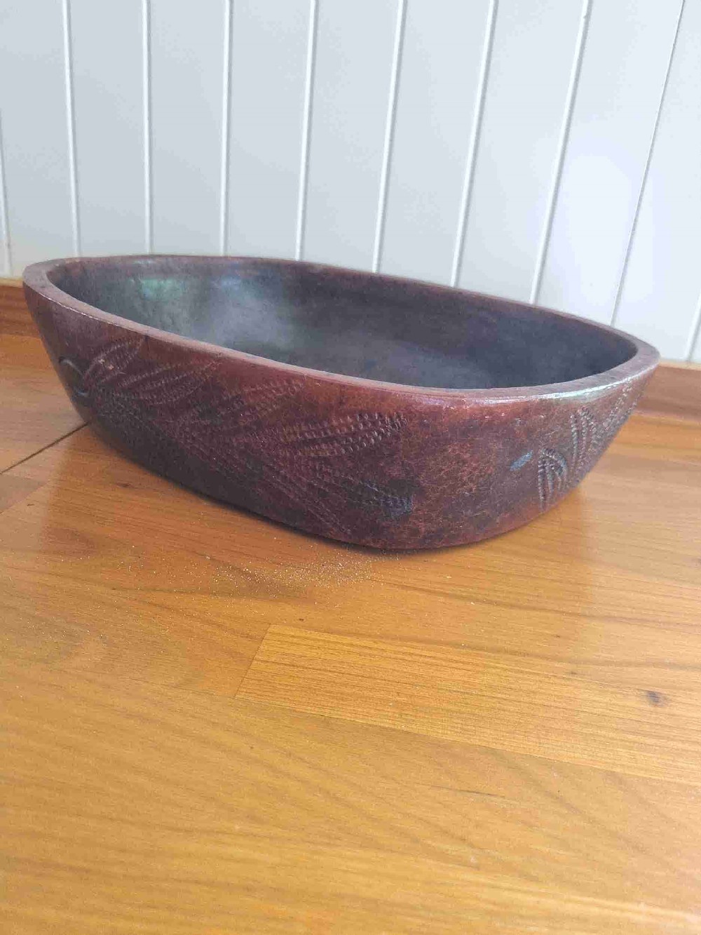 An oval 19th-century reddish-brown stoneware cooking dish featuring incised leaf patterns carved along the exterior side.