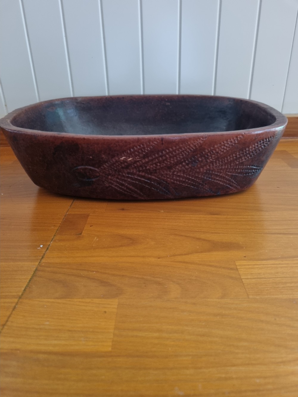 An oval 19th-century reddish-brown stoneware cooking dish featuring incised leaf patterns carved along the exterior side. View VI