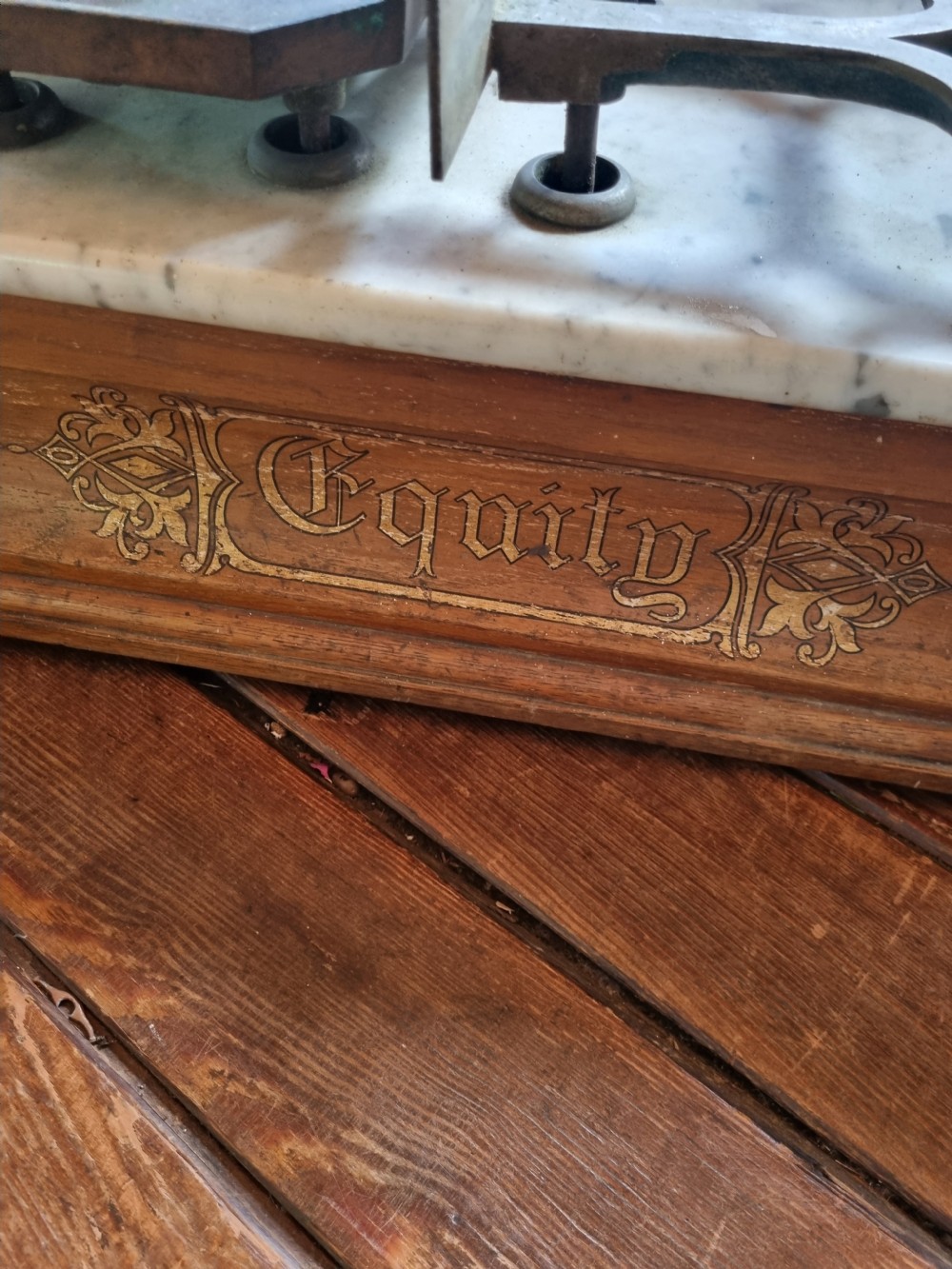 A Victorian grocer balance scale featuring a wooden base with gilded Equity lettering, a white marble slab surface, cast metal framework marked CWS, and nested brass weights. View II