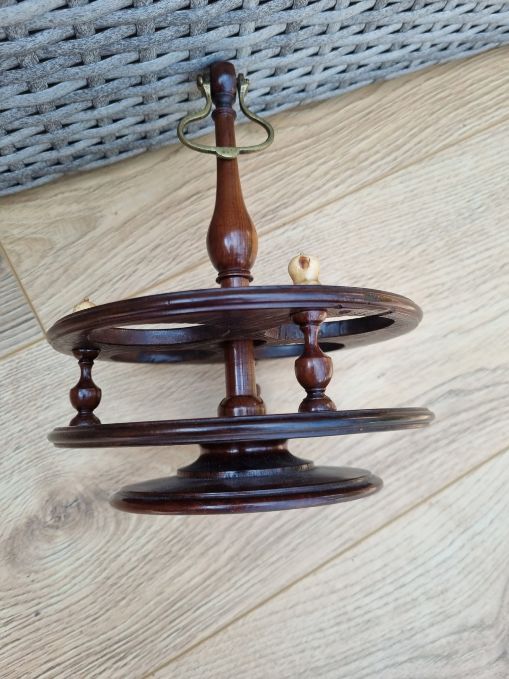 A Georgian turned mahogany four-bottle holder featuring a central brass loop handle, turned supports, and light bone finials. View II