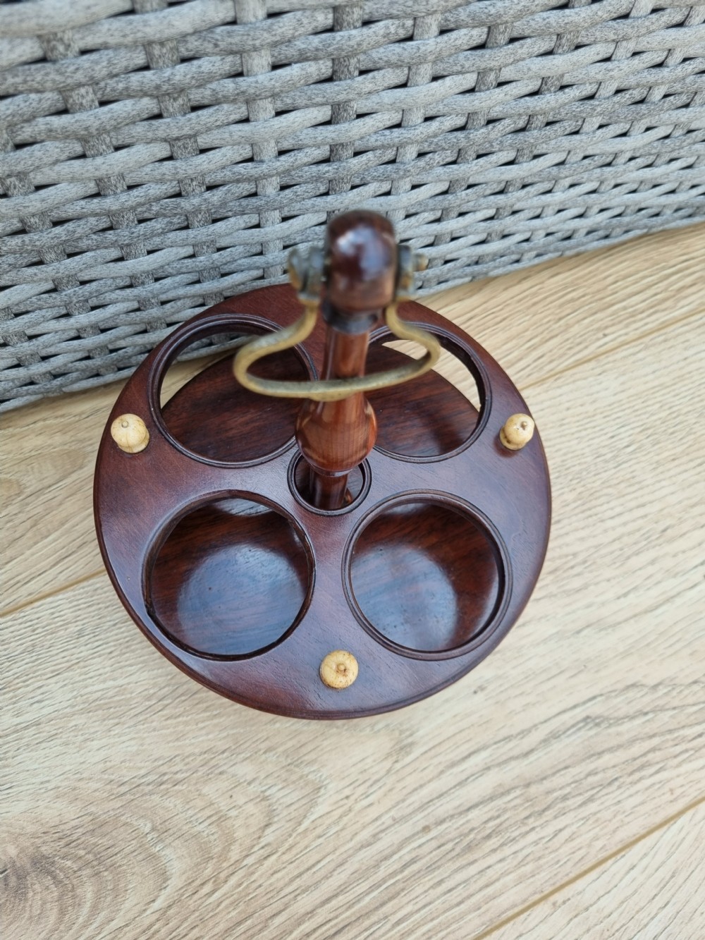A Georgian turned mahogany four-bottle holder featuring a central brass loop handle, turned supports, and light bone finials. View III