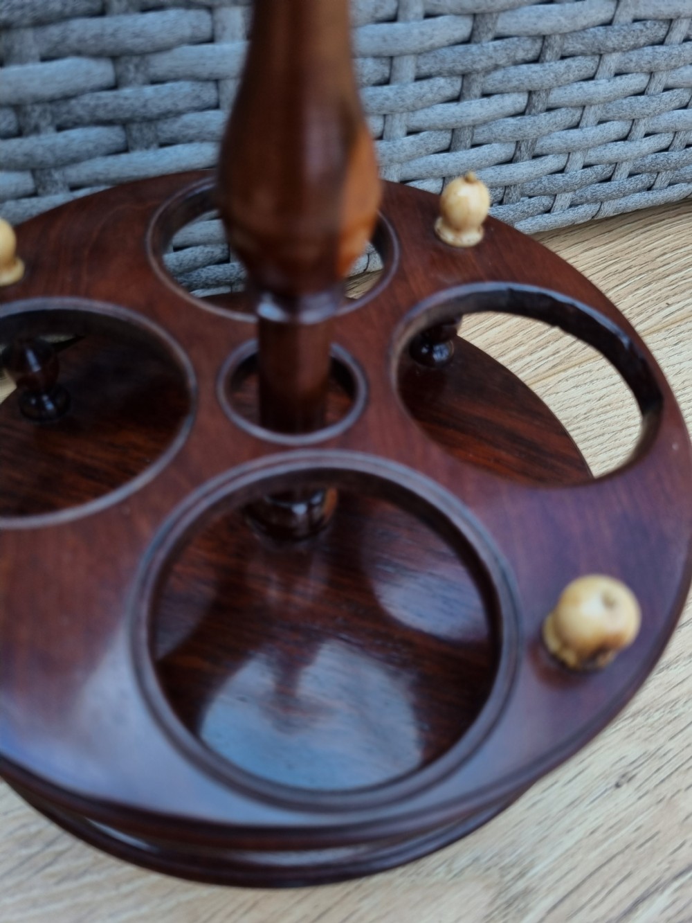 A Georgian turned mahogany four-bottle holder featuring a central brass loop handle, turned supports, and light bone finials. View V