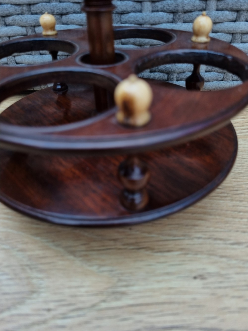 A Georgian turned mahogany four-bottle holder featuring a central brass loop handle, turned supports, and light bone finials. View VI