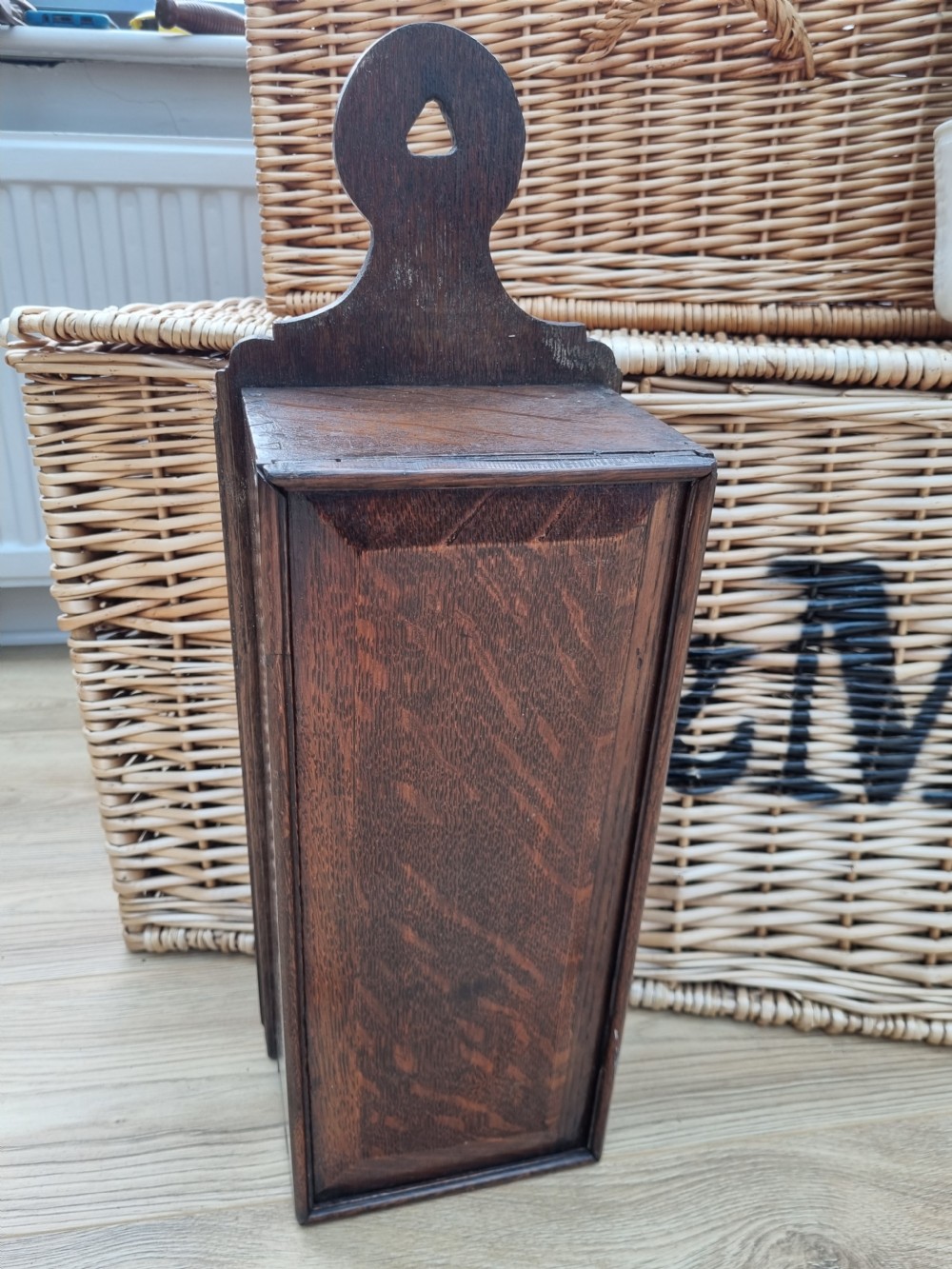 An antique dark oak hanging candle box featuring a shaped backboard with a wall-mounting aperture and a sliding front panel.