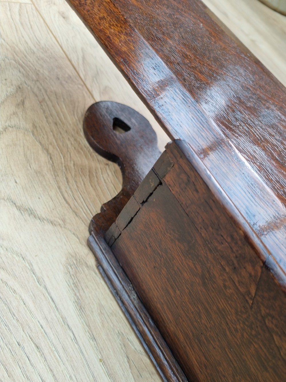 An antique dark oak hanging candle box featuring a shaped backboard with a wall-mounting aperture and a sliding front panel. View IV