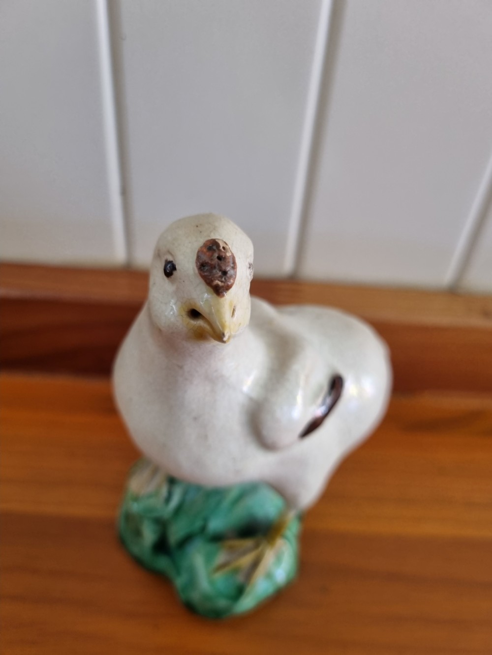 A late 18th-century Prattware glazed ceramic figure of a chicken standing on a textured green base. View IV